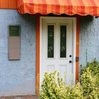 The door to the lower level of the building. blue walls and a orange and red striped awning.